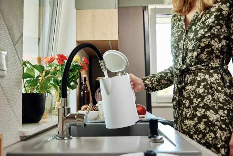 Woman filling a kettle from a tap