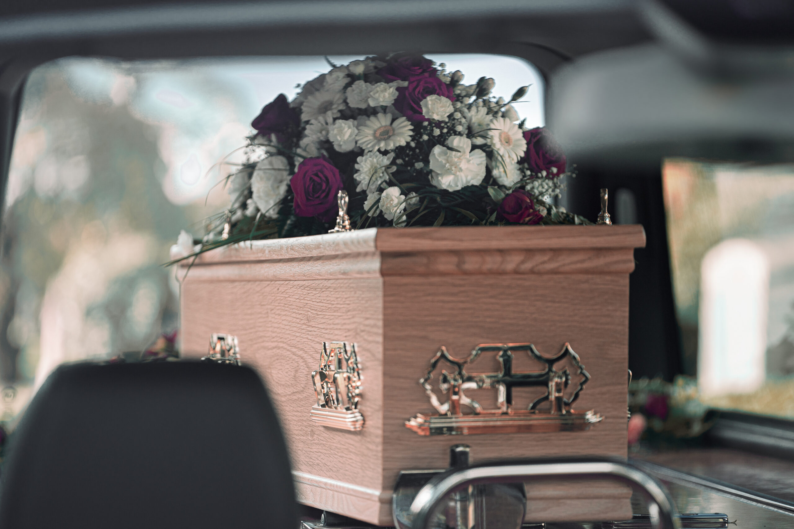 Coffin in a hearse with flowers to represent funeral costs.